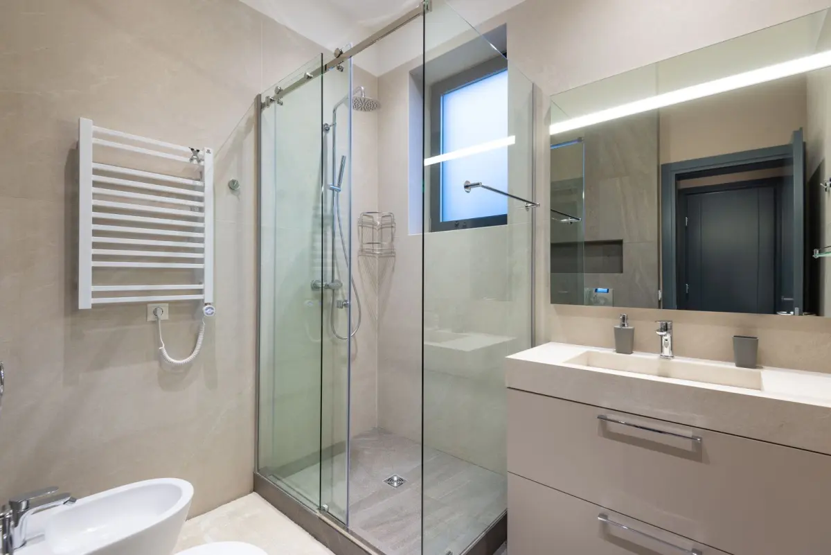 A walk-in shower with glass and tile
