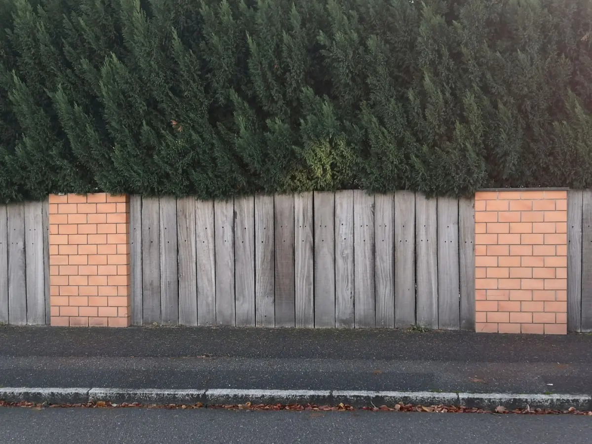 A wooden fence with brick pillars