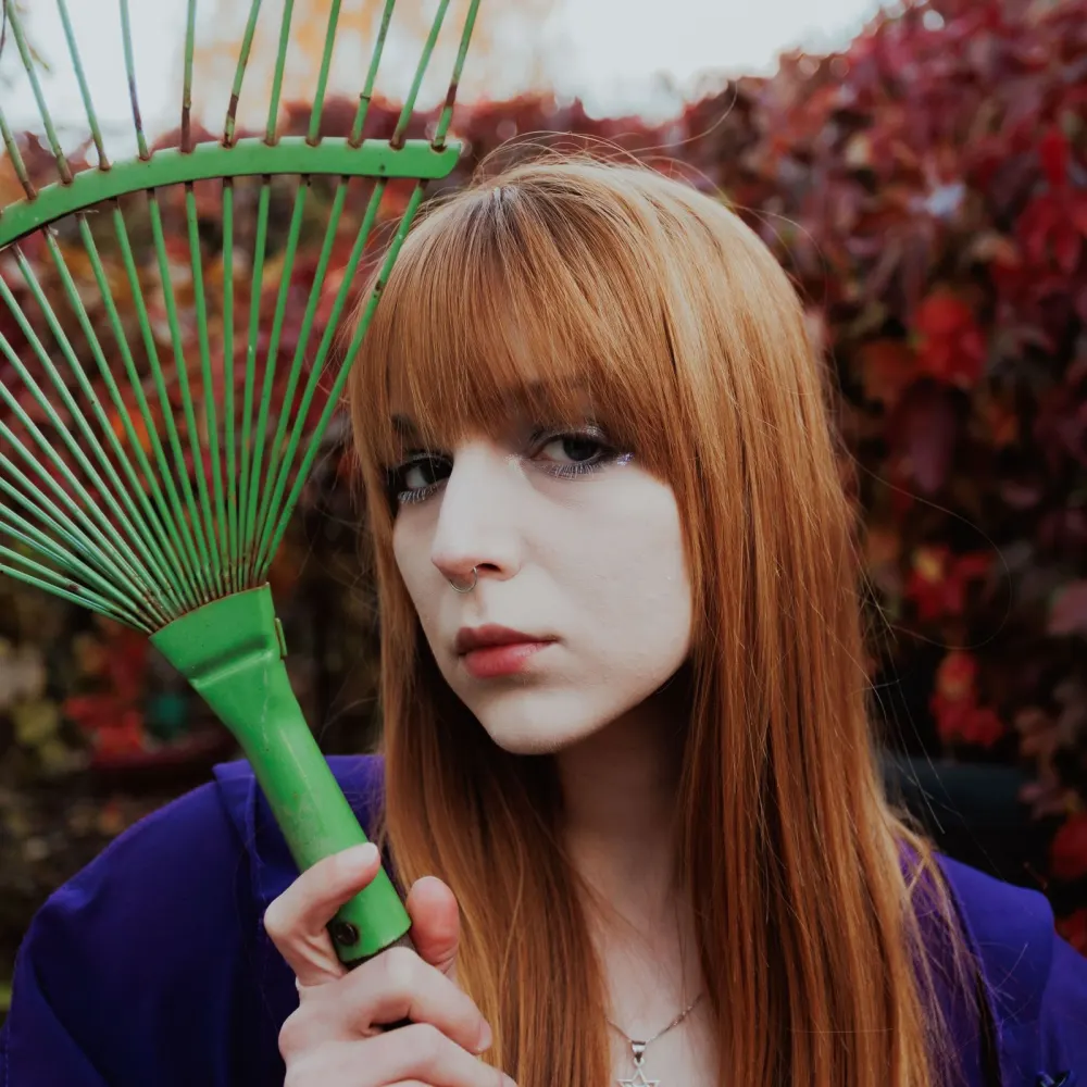The owner holding a rake, autumn leaves behind her