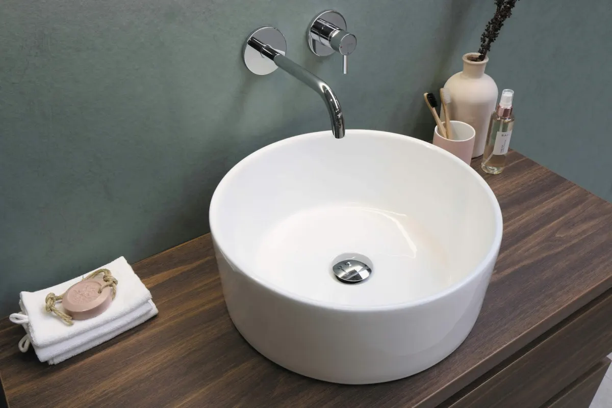 A white basin with a wall-mounted chrome faucet